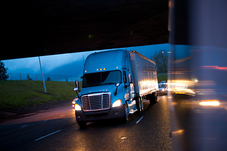 A semi-truck bearing down the freeway at high speeds